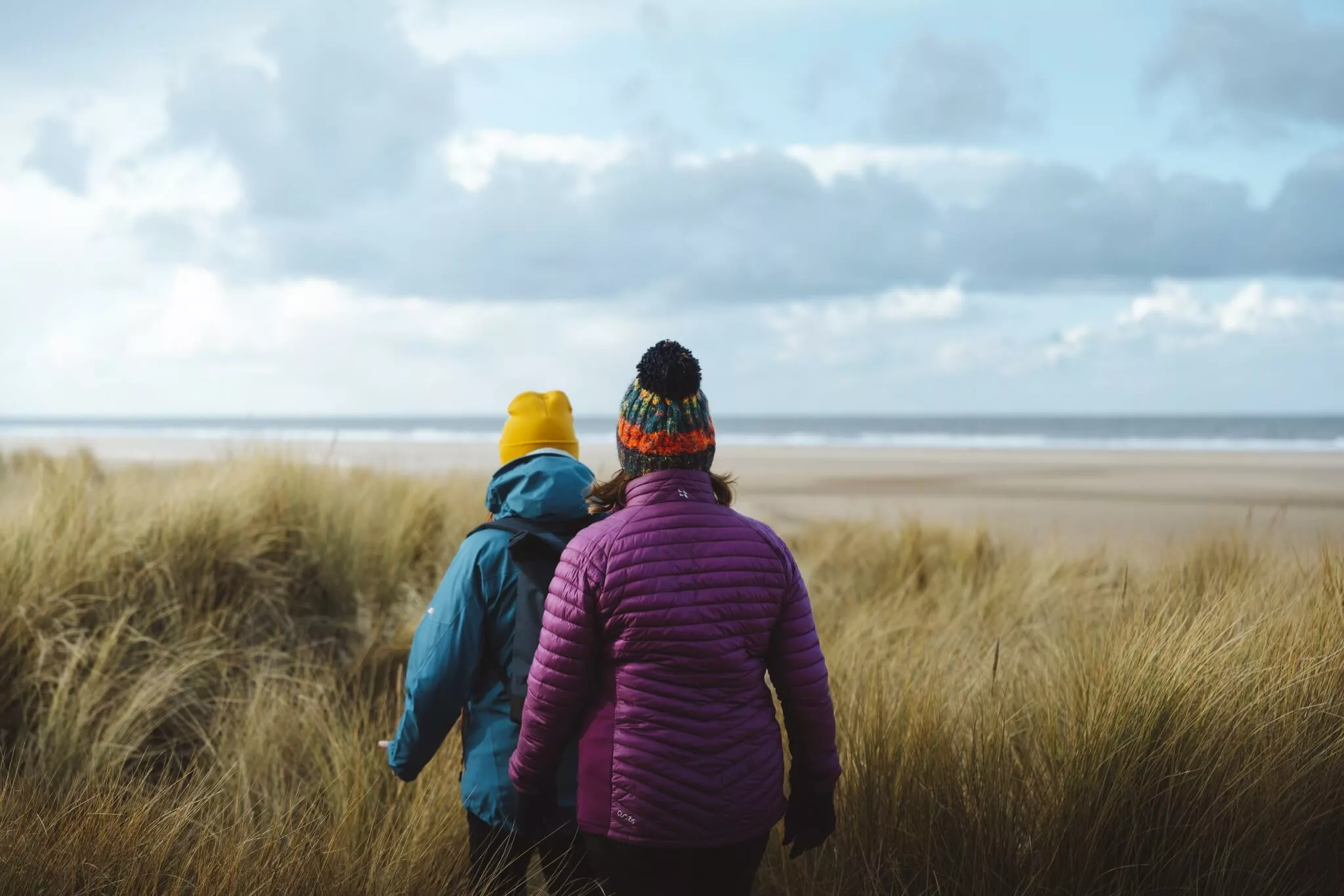 Two people walking through the dunes at Holkham beach