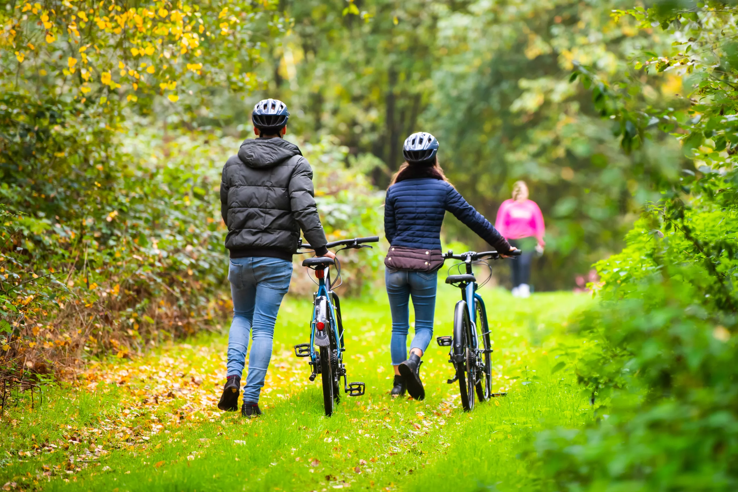 Couple pushing bikes in woodland