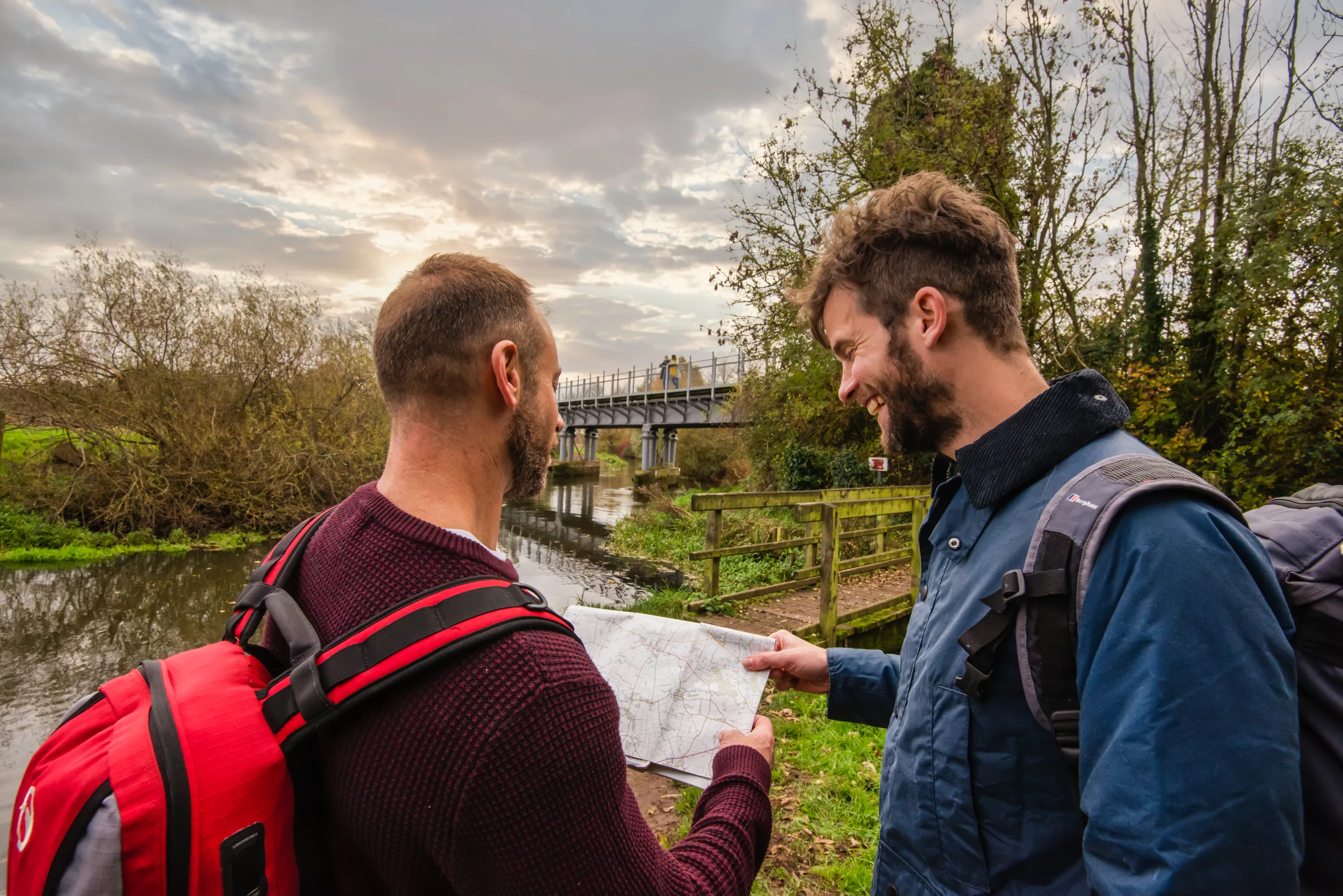 Two men looking at a map by the river Bure