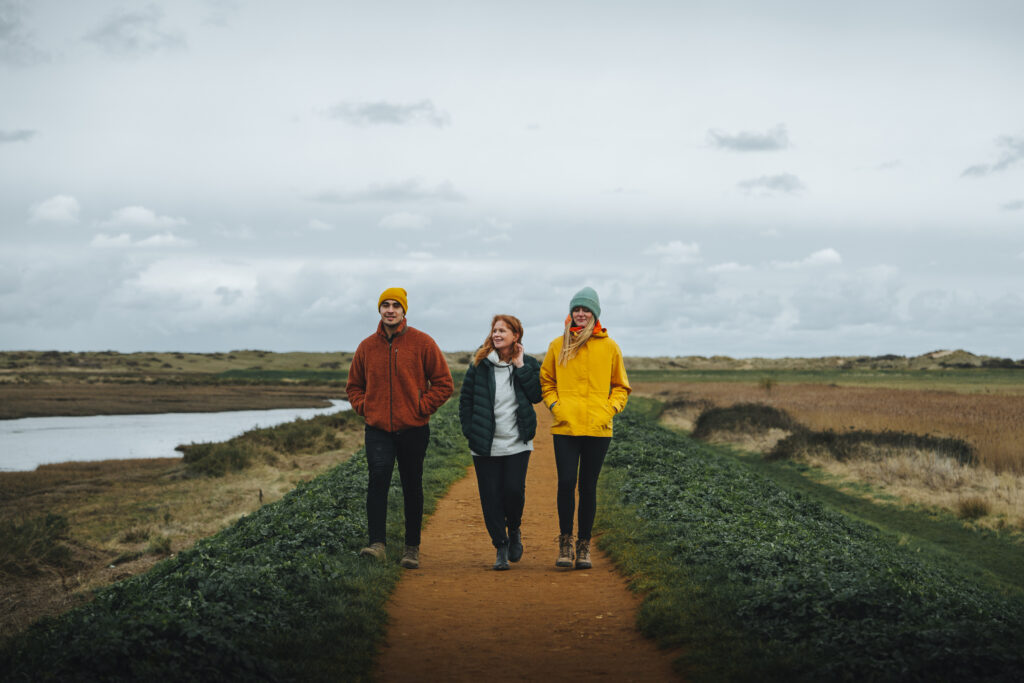 A group of three people walking on a coastal path