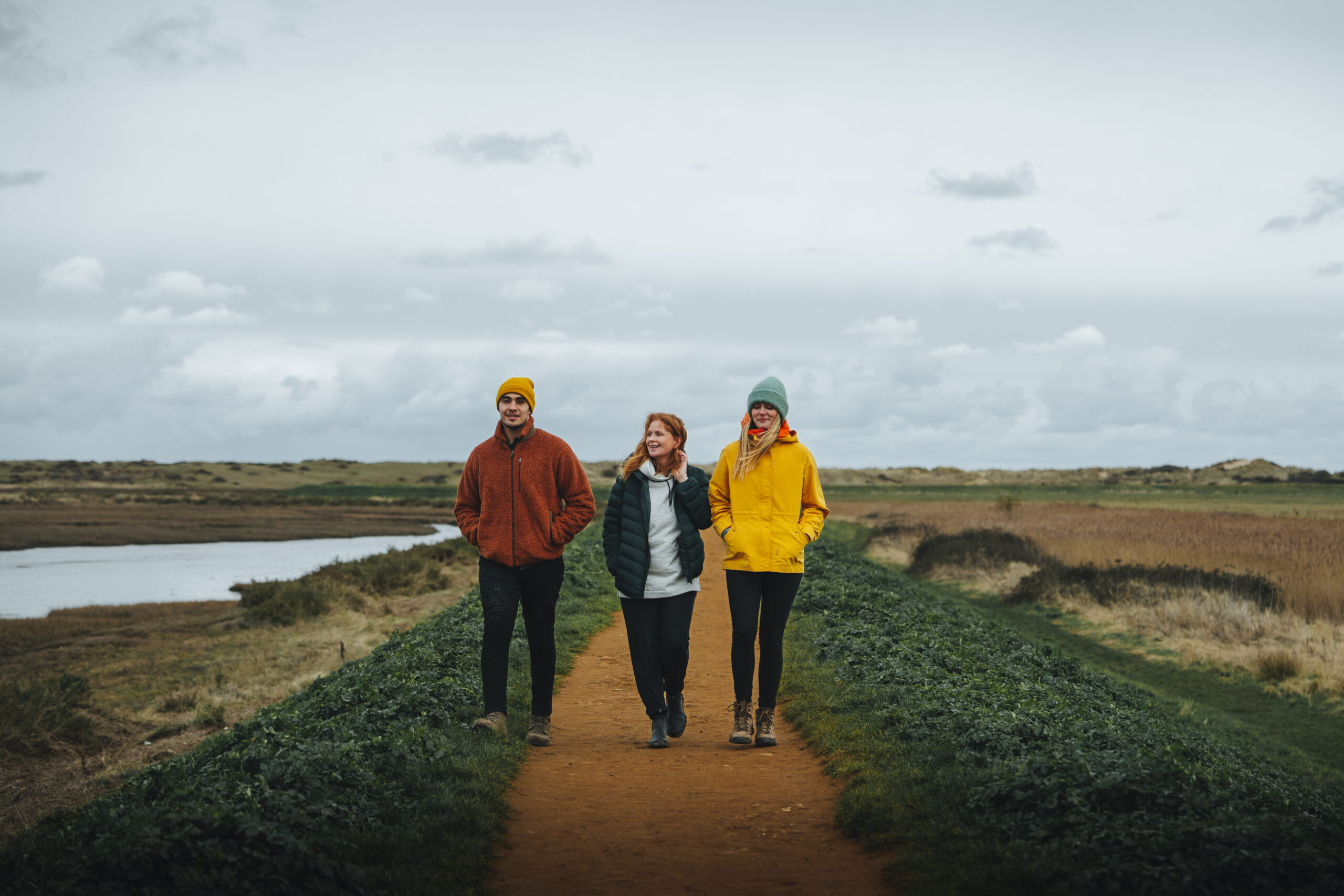 A group of three people walking on a coastal path