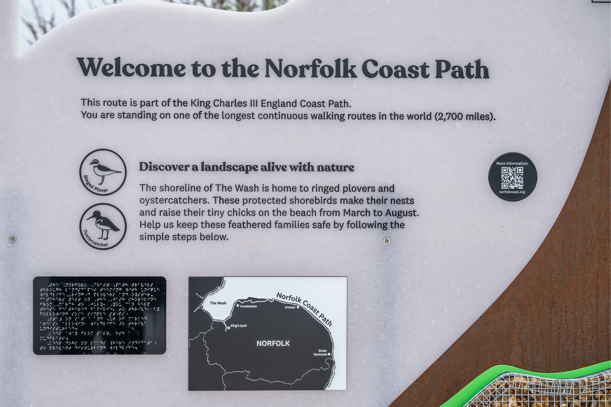 A close up of one of the interpretation panels, showing information about the local wildlife, a map of the Norfolk Coast and a panel of braille.