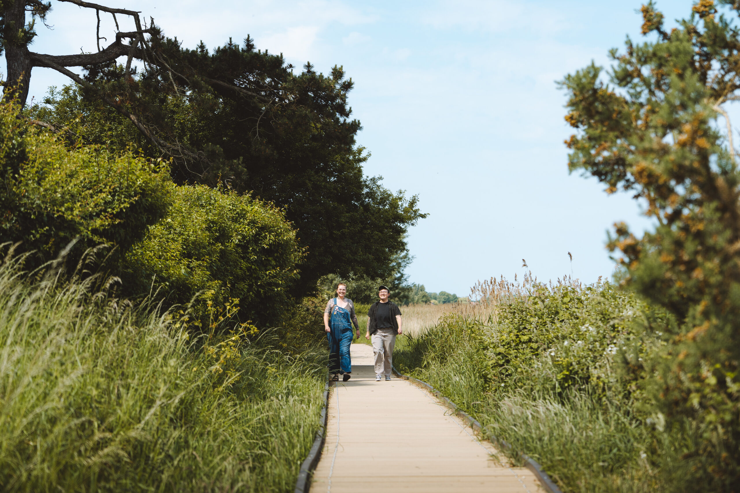 Two people walking on a boardwalk.