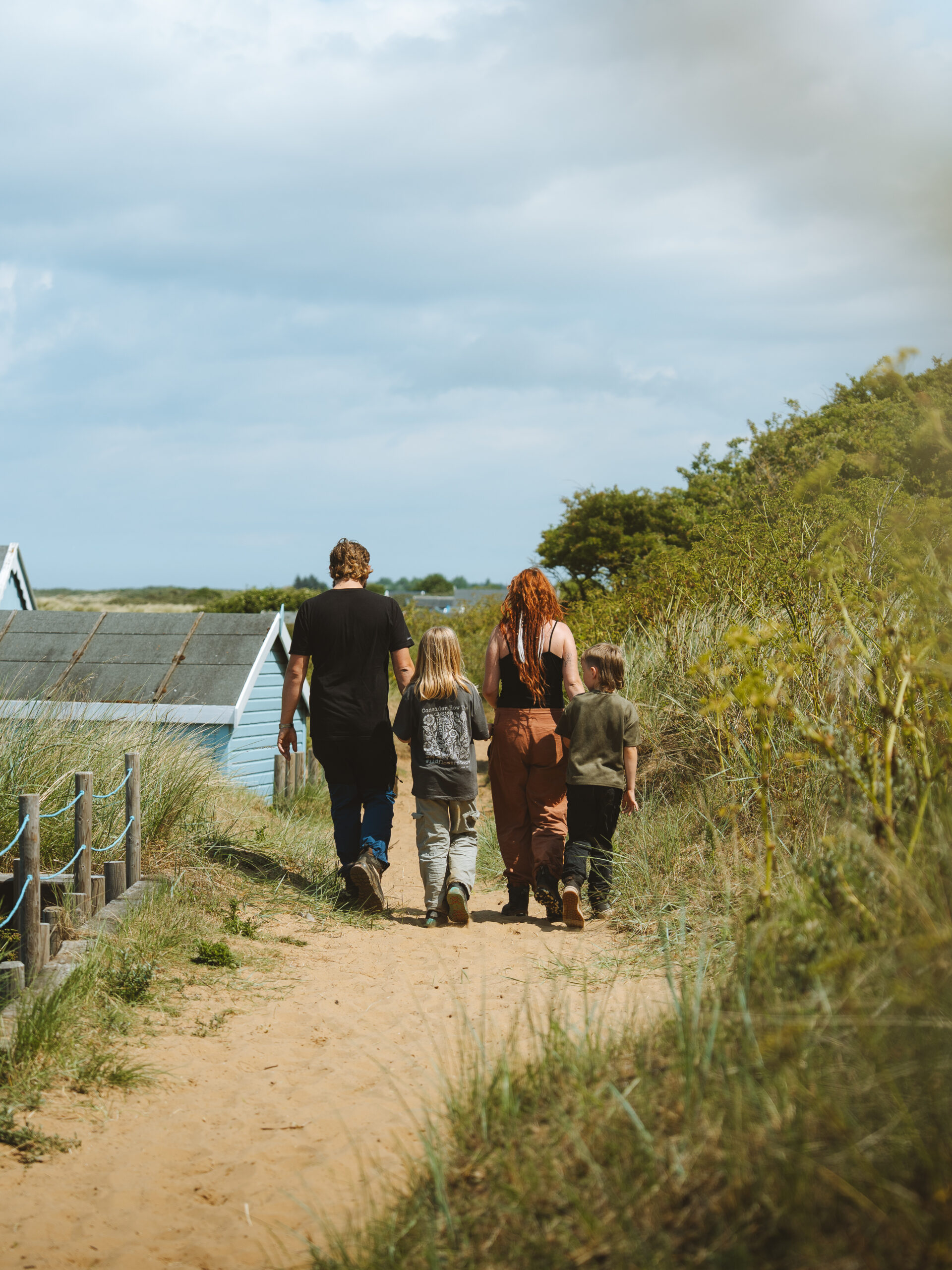 A family of four walking along a sandy path.