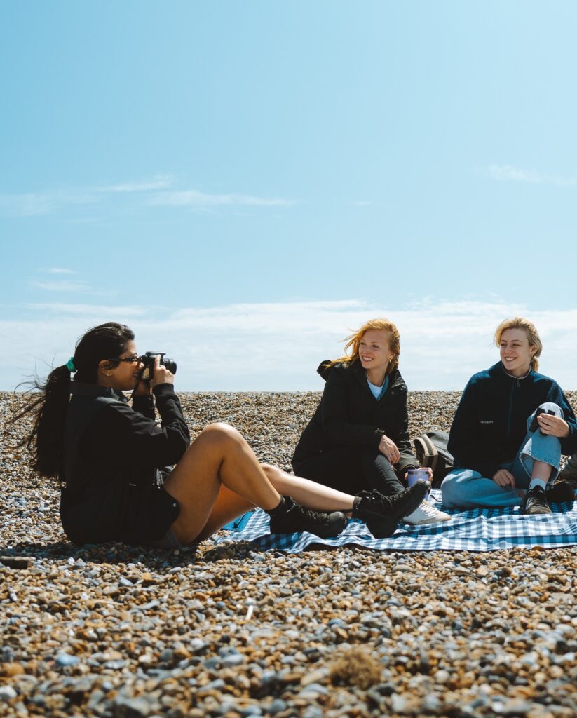 3 friends on a picnic blanket at the beach