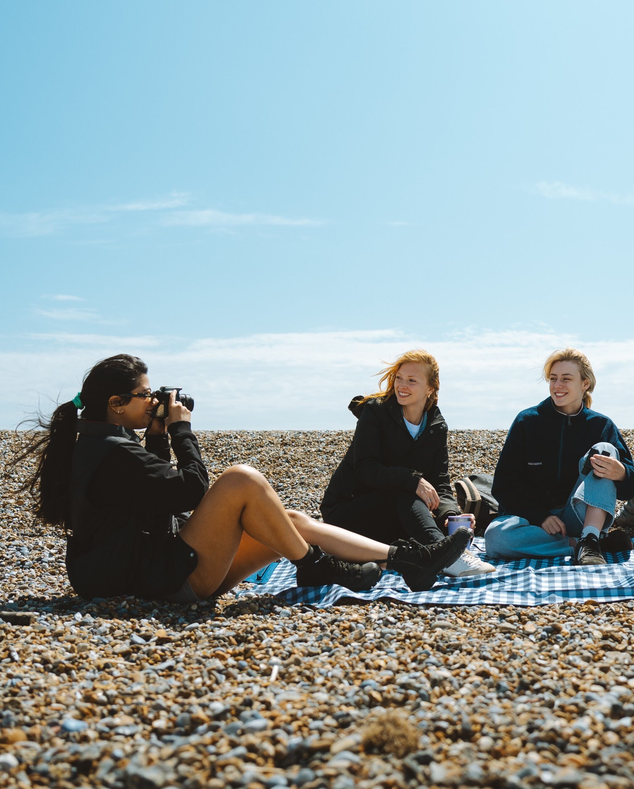 3 friends on a picnic blanket at the beach